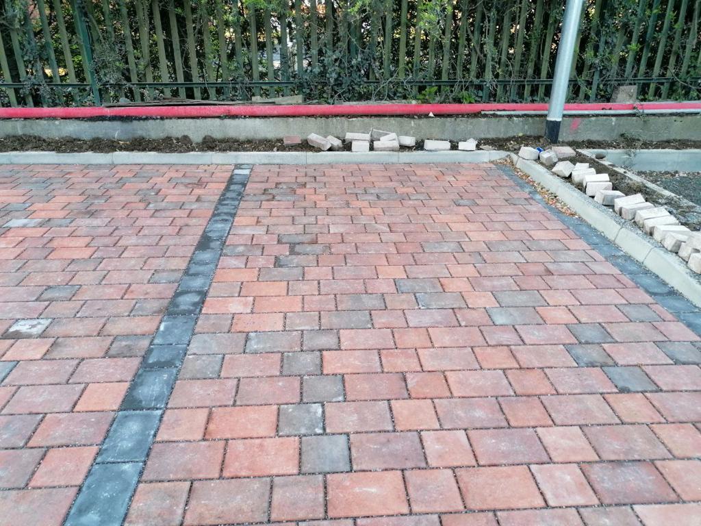 A brick pavement with a black fence and a black line in the background